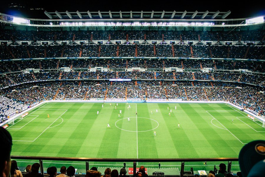 Fotbollsarena med en grön plan och fullsatta läktare